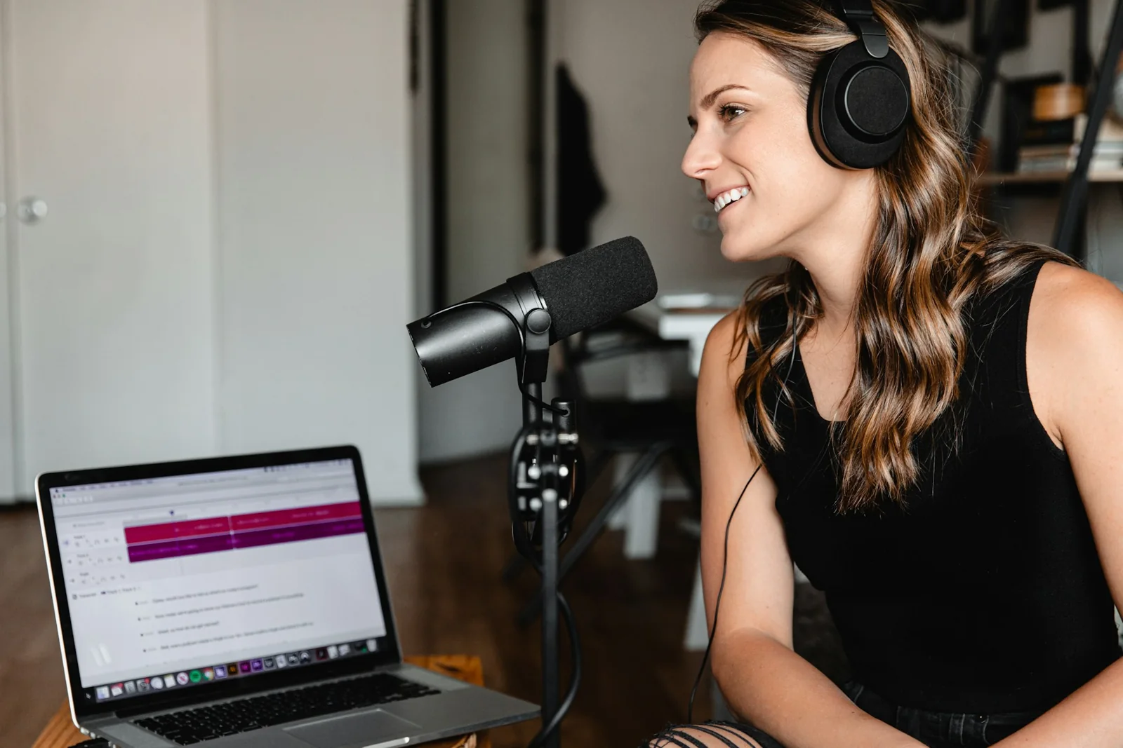 A woman wearing headphones and speaking into a studio microphone